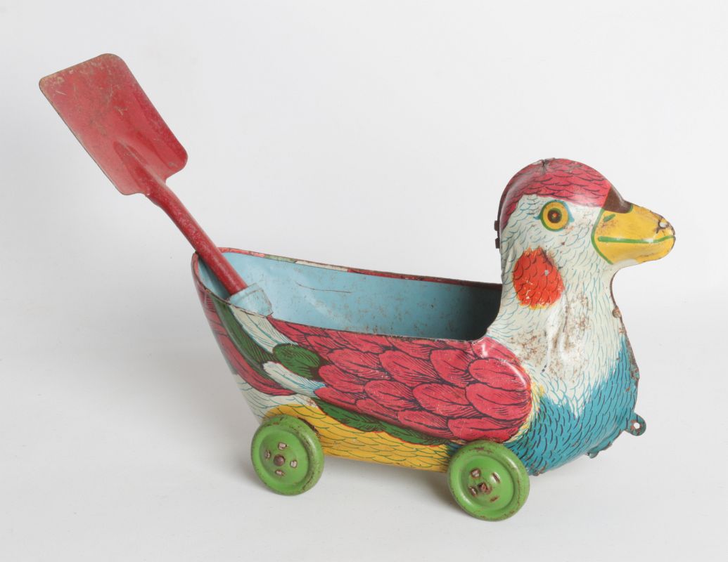 A DUCK FORM TIN LITHO DRAG-A-LONG WITH SHOVEL
