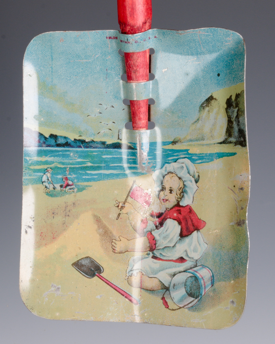 A CHILD'S TIN LITHO SAND SHOVEL WITH WOOD HANDLE