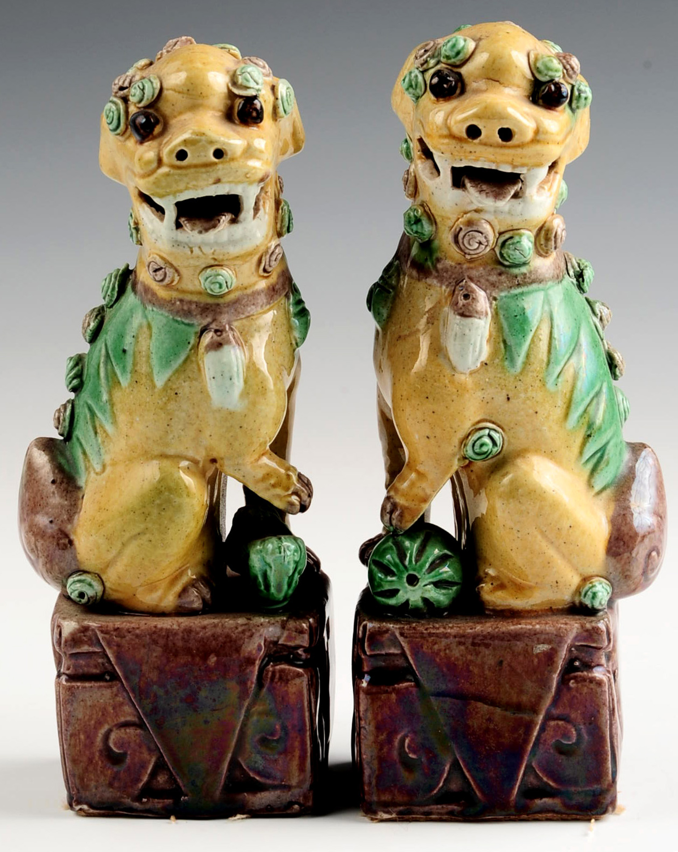 A PAIR OF EARLY 20TH CENTURY GLAZED FOO DOG FIGURE