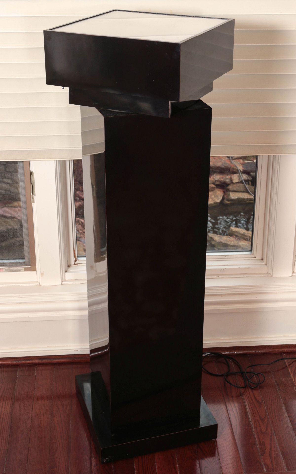 A BLACK ACRYLIC LIGHTED REVOLVING PEDESTAL