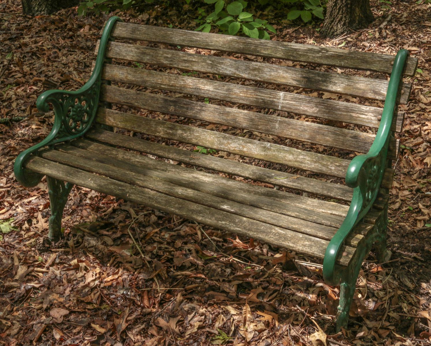 AN OUTDOOR GARDEN BENCH WITH CAST IRON ENDS