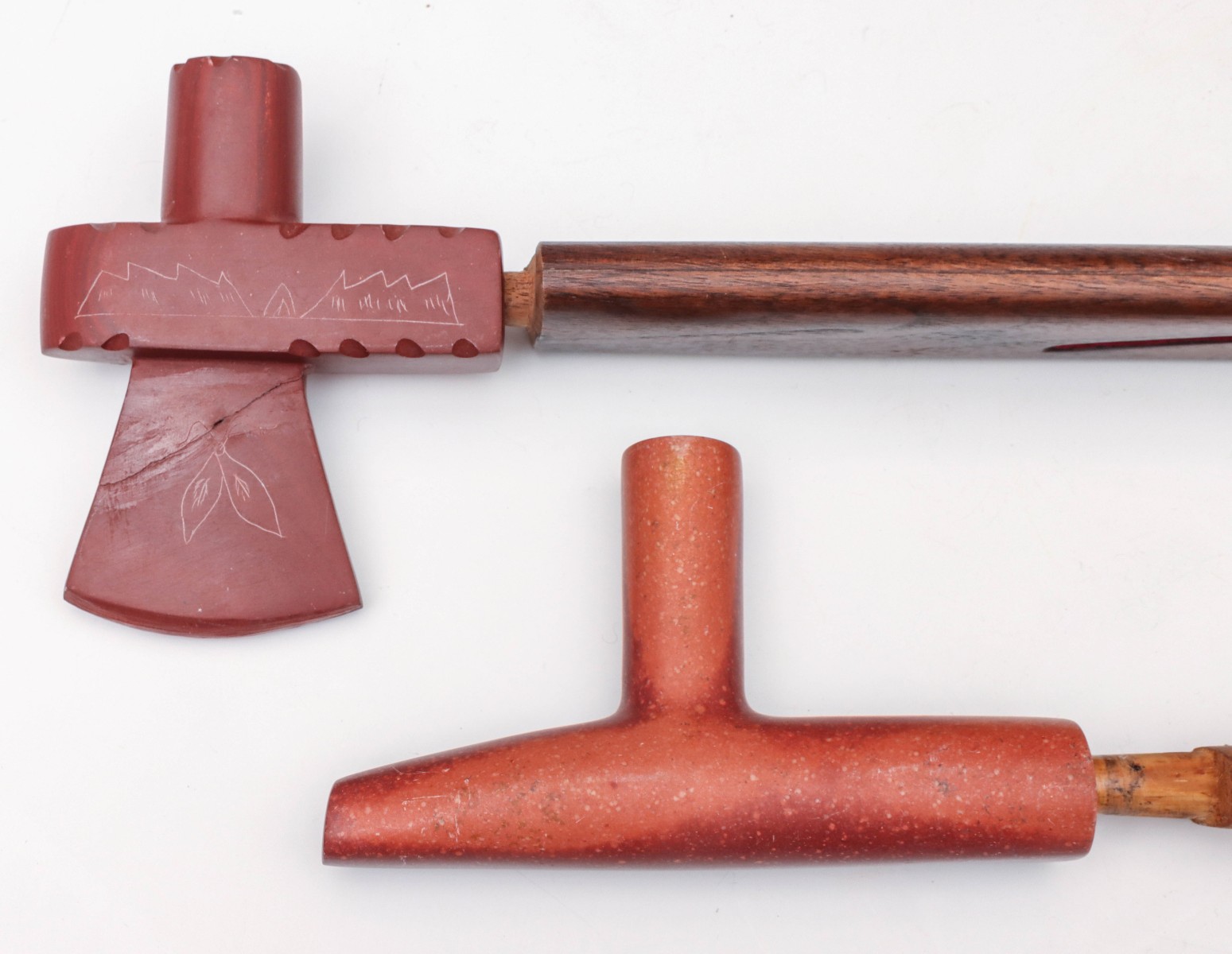 TWO CARVED CATLINITE PIPE BOWLS WITH WOOD STEMS