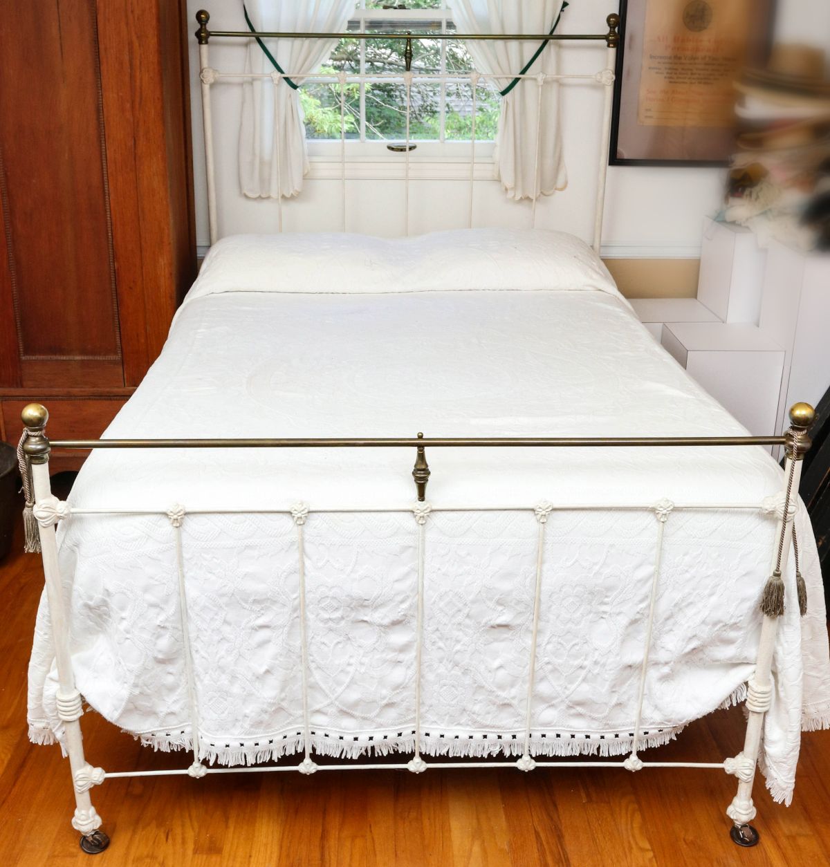 AN ANTIQUE IRON BED WITH BRASS ORNAMENT