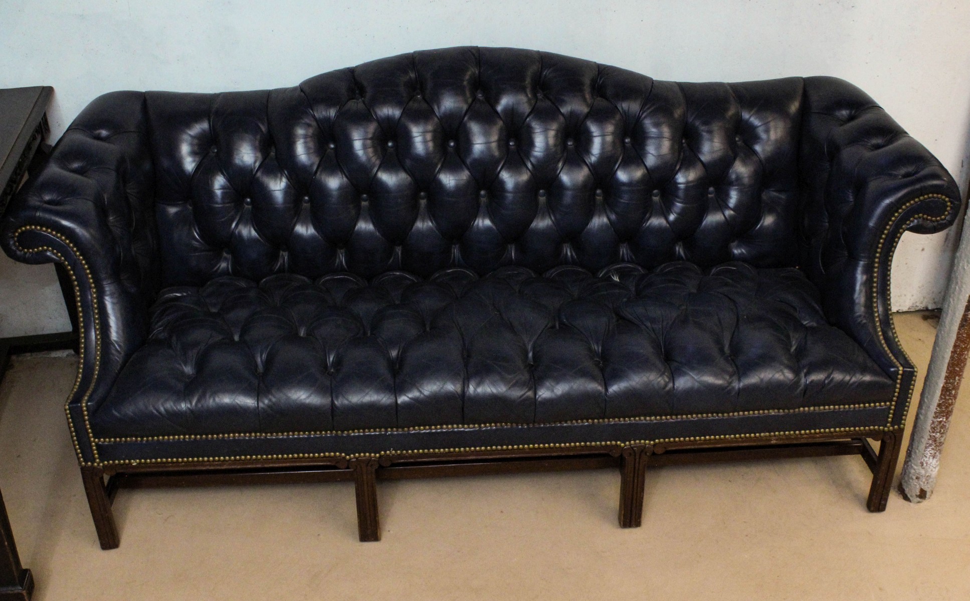 A BUTTON TUCKED CAMEL BACK SOFA WITH BRASS TACKS