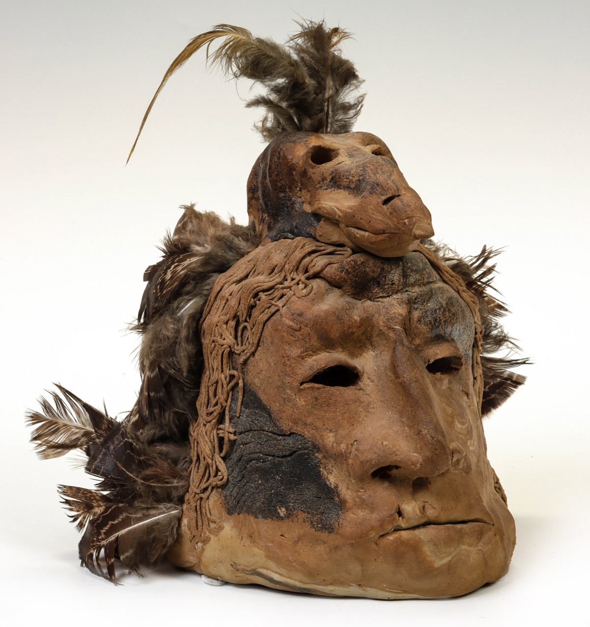 A STONEWARE PORTRAIT OF WARRIOR WITH RAVEN HEADDRESS