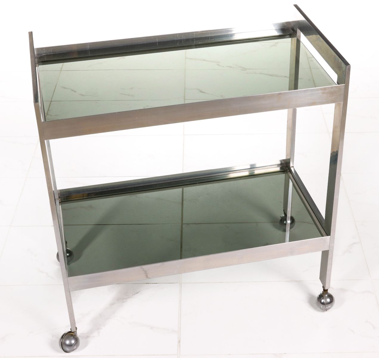 A MODERN TWO-TIER CHROME BAR CART WITH TINTED GLASS