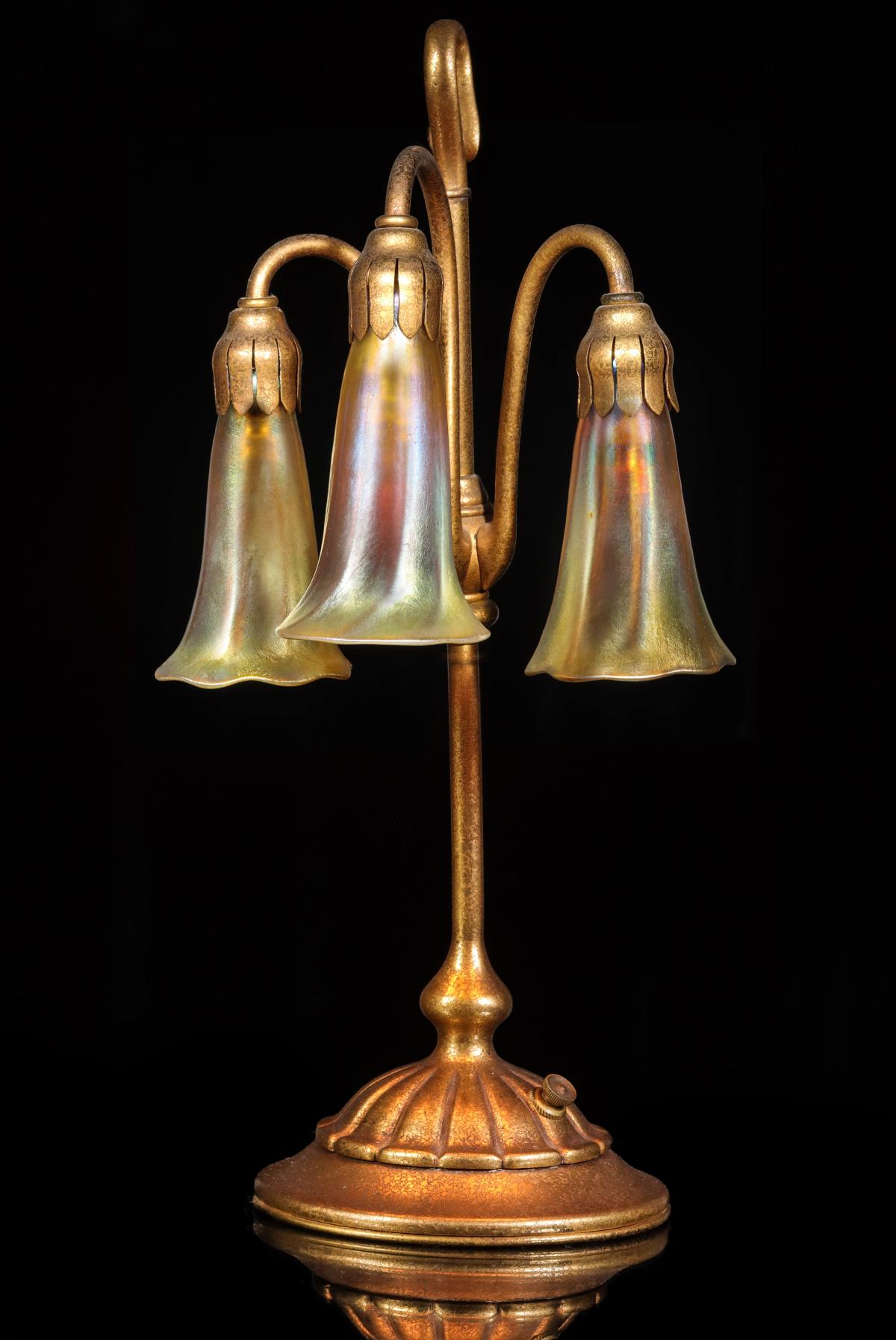 A GOOD TIFFANY STUDIOS BRONZE THREE LIGHT LILY LAMP