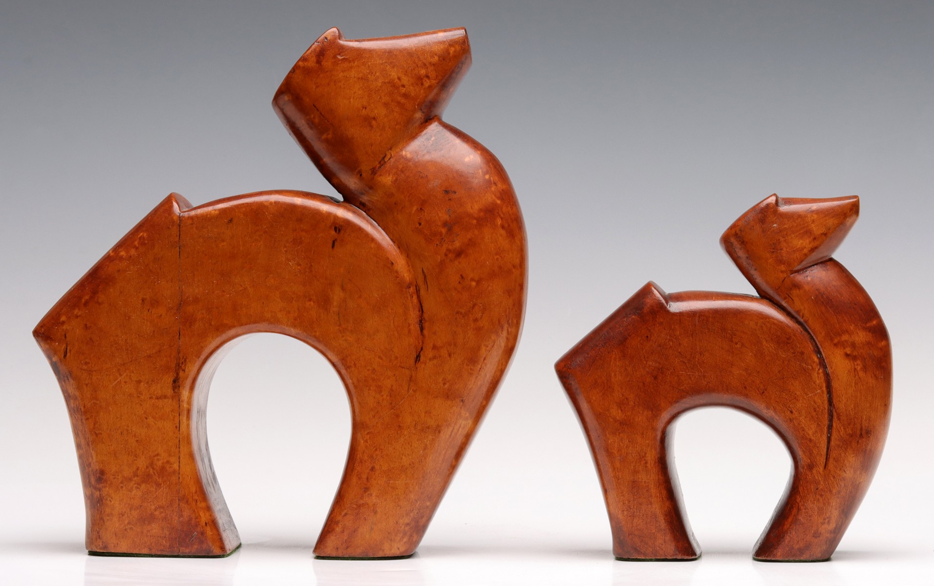 A PAIR CARVED BIRD'S EYE MAPLE STYLIZED CAMEL FIGURES