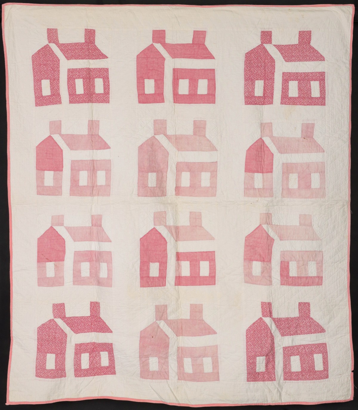 A PINK AND WHITE CALICO SCHOOLHOUSE PATTERN QUILT