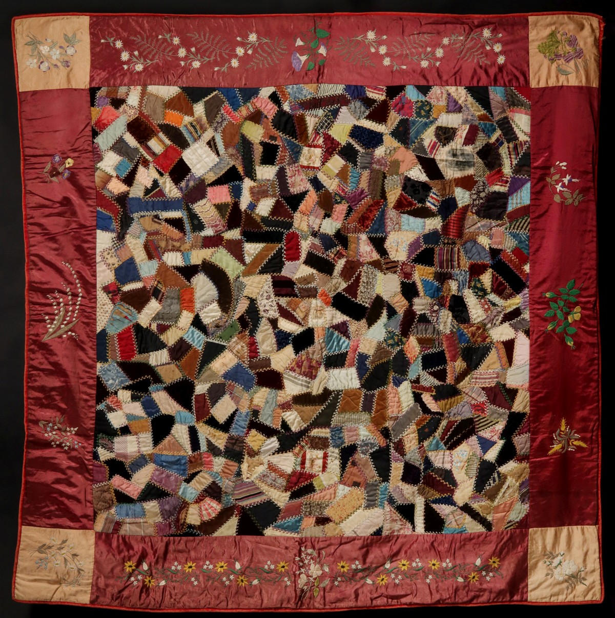 AN UNUSUAL CRAZY QUILT WITH EMBROIDERED SILK BORDER