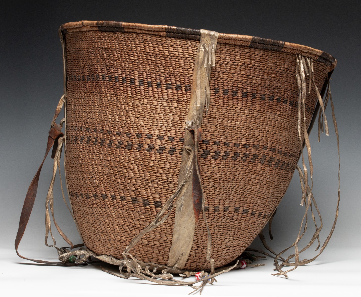 A GOOD 19TH CENT APACHE BURDEN BASKET WITH RAWHIDE