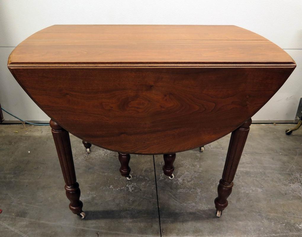 AN OVAL WALNUT DROP-LEAF TABLE